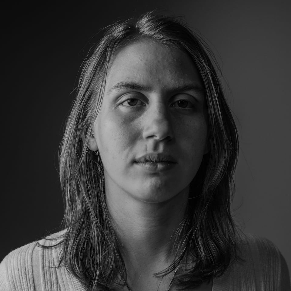 Black-and-white portrait of a woman with shoulder-length hair, lit hard from one side.