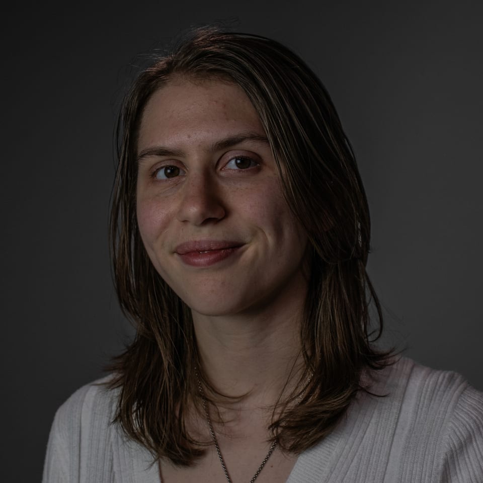 Close portrait of a woman with a soft half-smile, lit from one side.