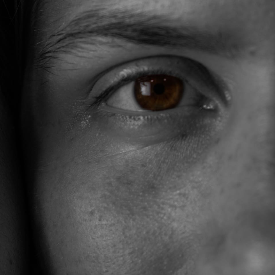 Extreme close-up of a single brown eye, the rest of the frame in black and white.