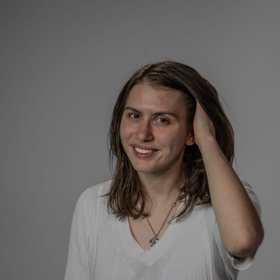 Smiling woman with shoulder-length hair running one hand through it.