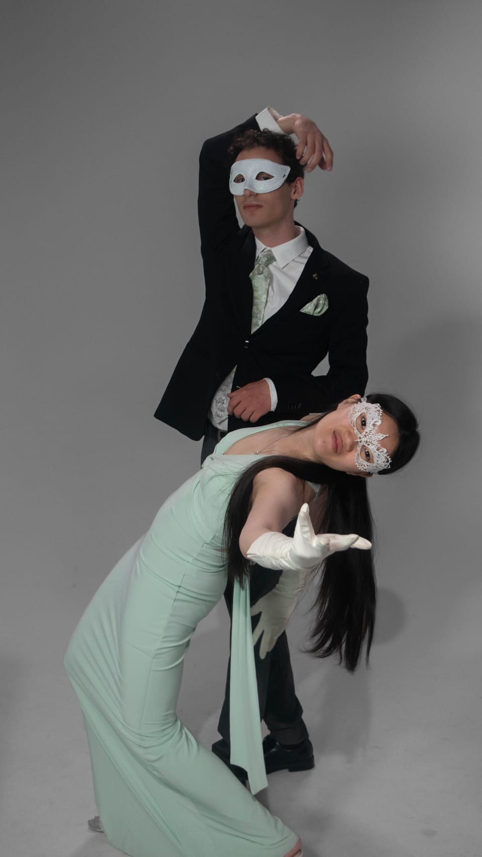 A man in a white masquerade mask dips his partner into a deep backbend.