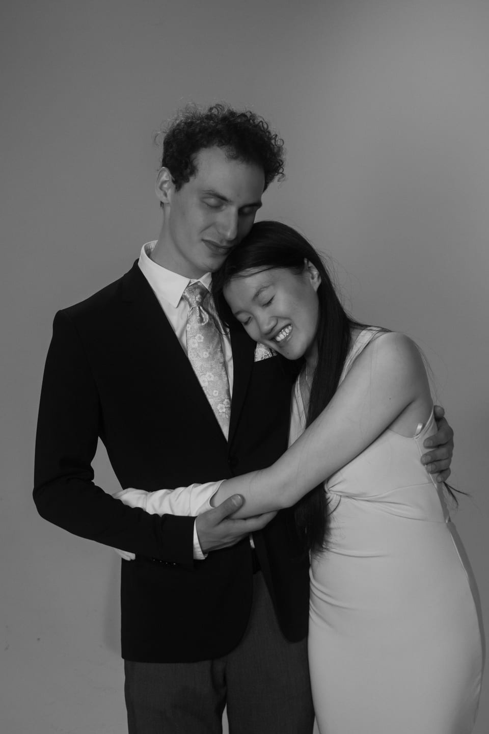 Black-and-white photo of a couple embracing, her head resting on his shoulder.