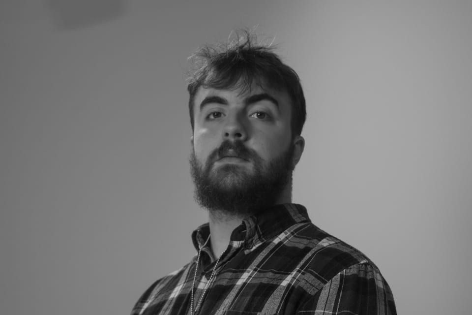 Black-and-white portrait of a bearded man in a plaid flannel shirt.