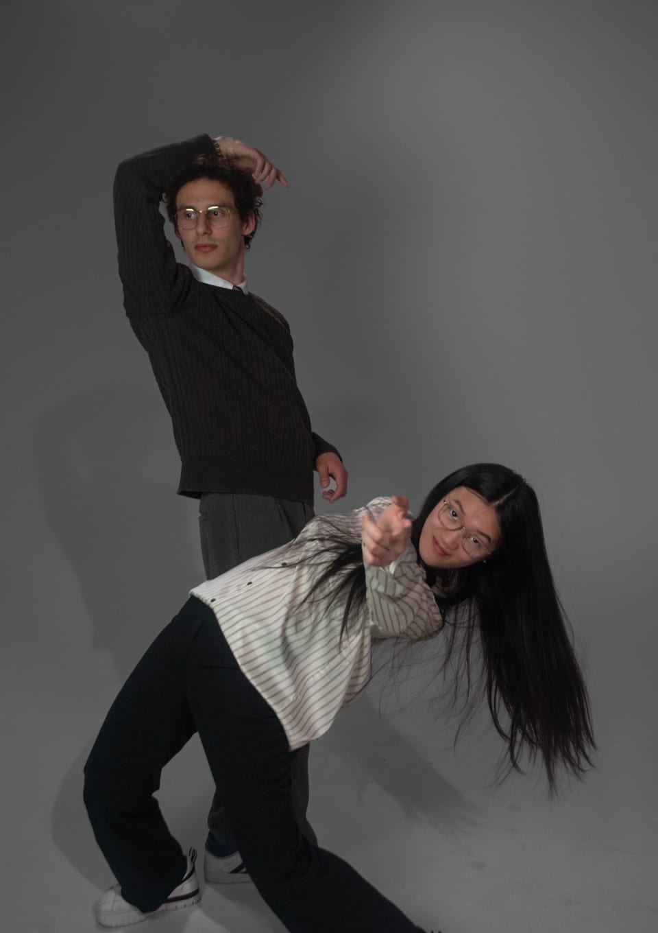 Two dancers in a dramatic pose: one with an arm over his head, the other leaning back with her hair swinging.