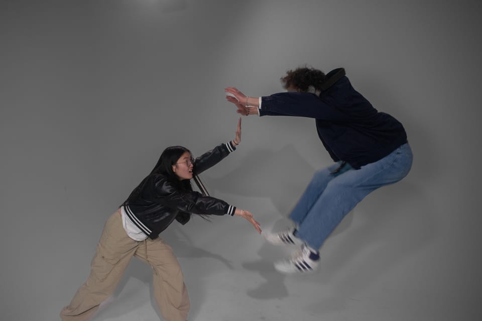 Two people frozen mid-leap, reaching for each other's hands.