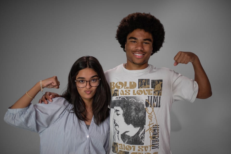 A young man and woman side by side, flexing their arms for the camera.