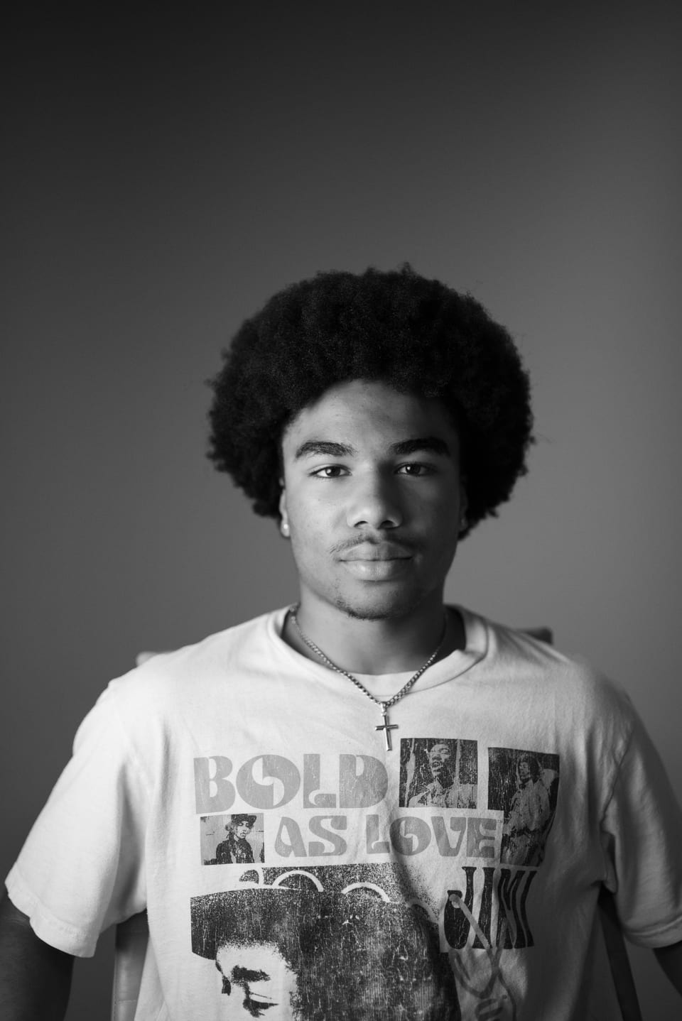 Black-and-white portrait of a young man with an afro, a small cross necklace and a Jimi Hendrix T-shirt.