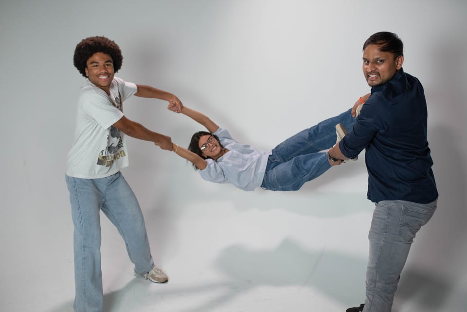 Two men swinging a laughing young woman between them by her arms and legs.