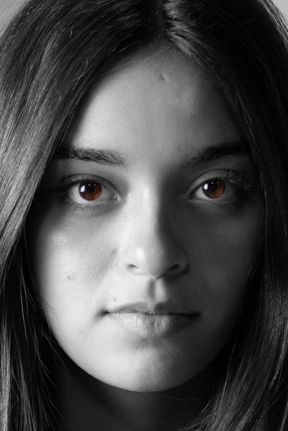 Black-and-white close-up of a young woman's face, looking straight into the lens.