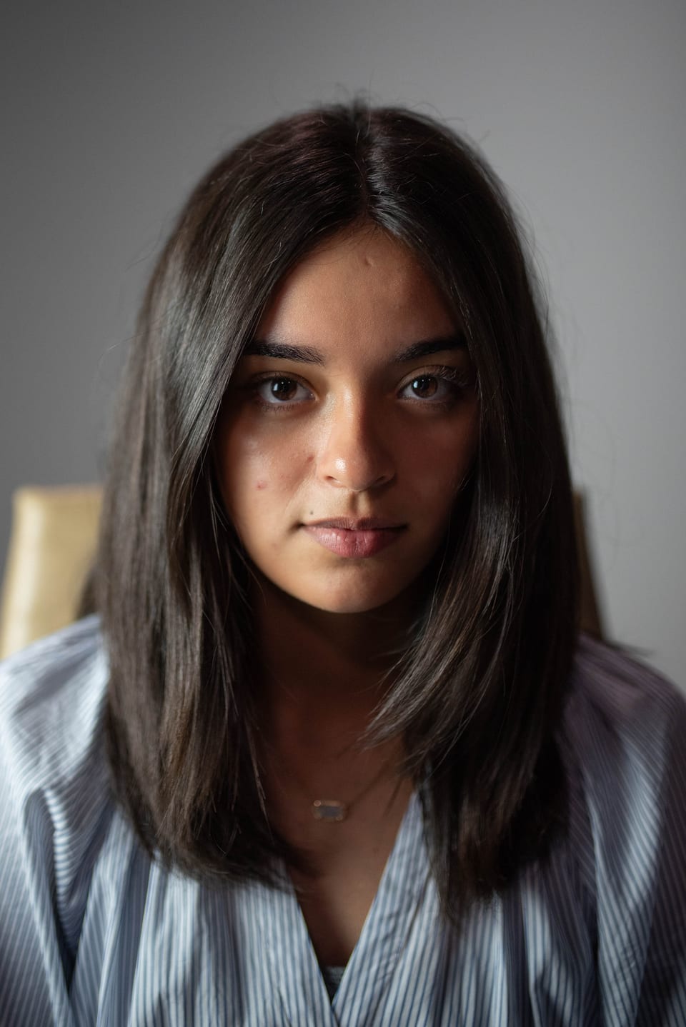 Portrait of a young woman with straight dark hair, looking directly at the camera with a calm expression.